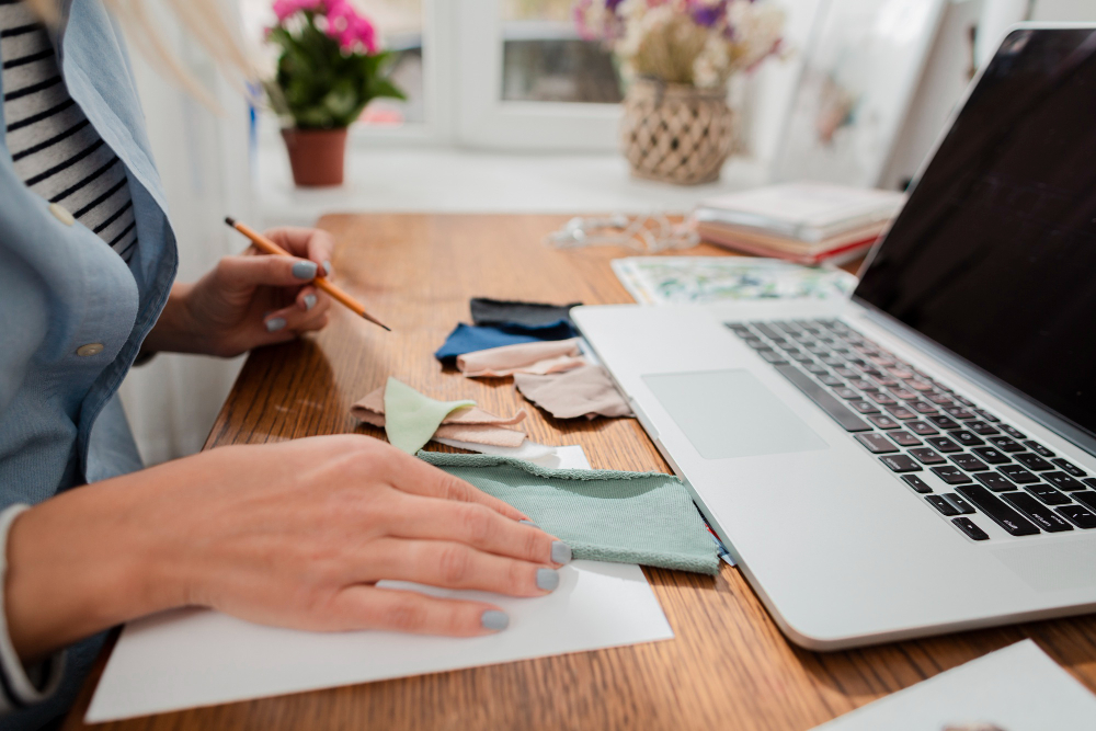 Promotional banner for 'Instant Course Composer: How To Craft Amazing Courses with ChatGPT'. A person is seen at a wooden desk with fabric swatches, a pencil, and a laptop. The text highlights how the tool helps users brainstorm course ideas, create outlines, and generate content using ChatGPT, eliminating writer’s block and streamlining the process.